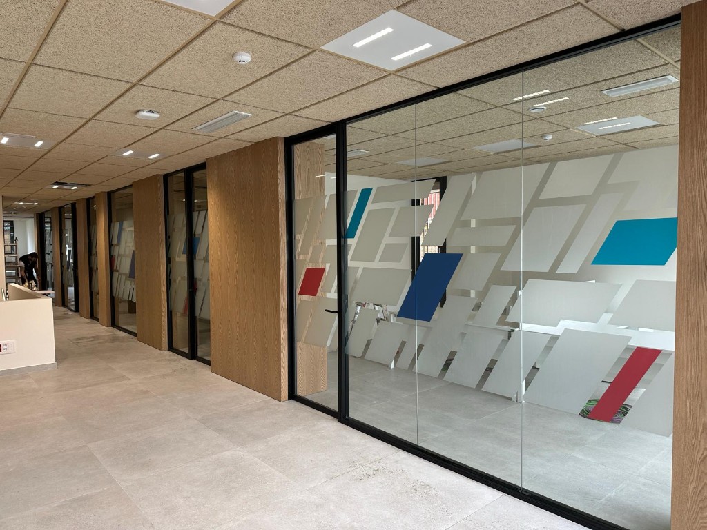 Pasillo de oficinas de Ambulàncies Tomàs con mamparas de cristal viniladas con diseño corporativo